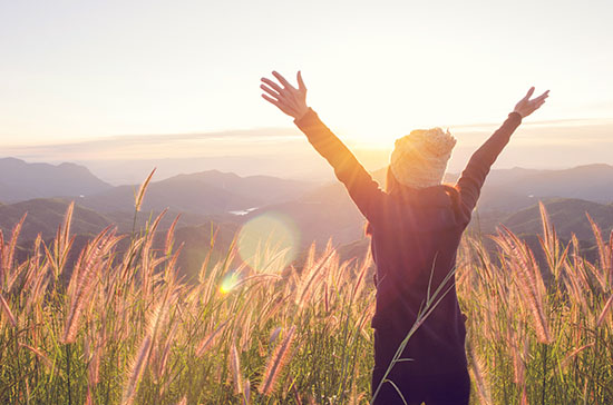Carefree Happy Woman Enjoying Nature on grass meadow on top of m